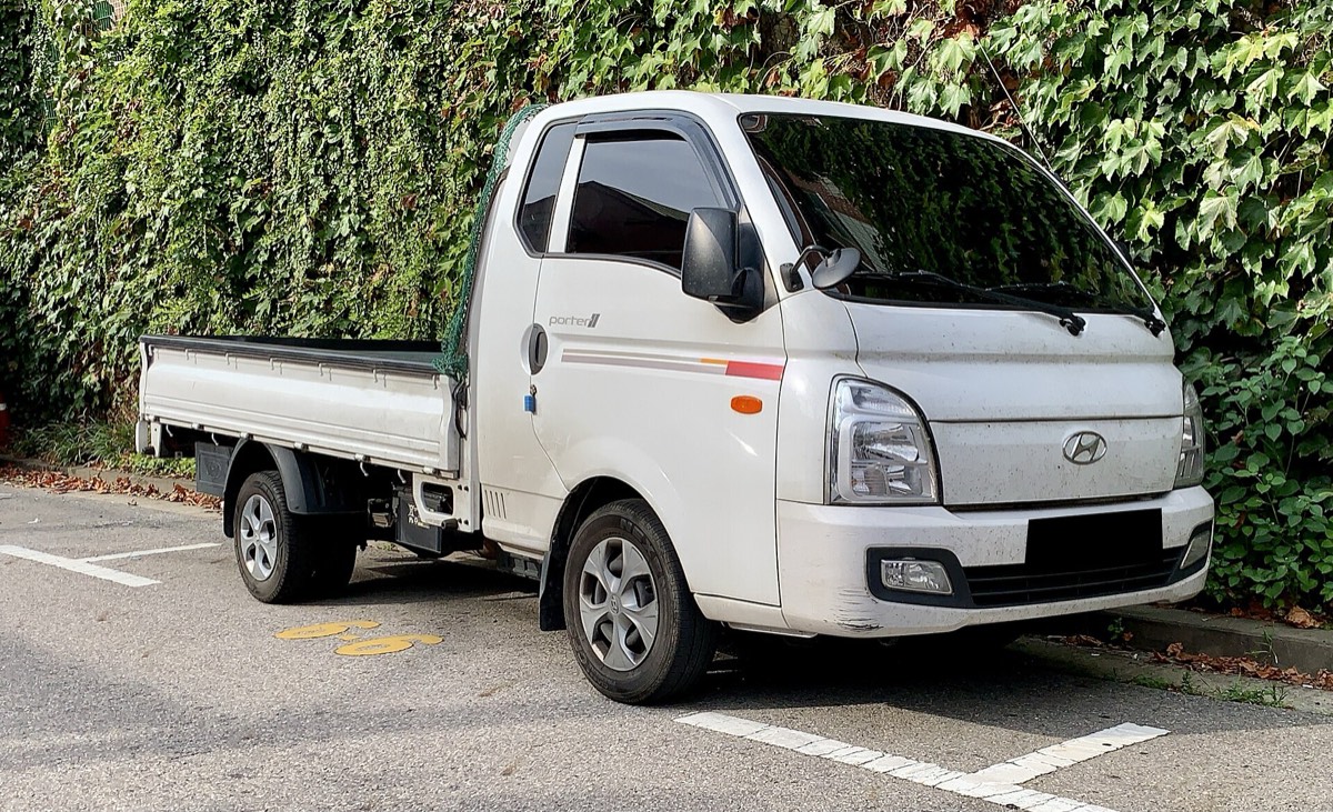 Beyaz Hyundai H100 açık kasa kamyonet, önden yandan görünüm. Kasası boş ve üstü açık.