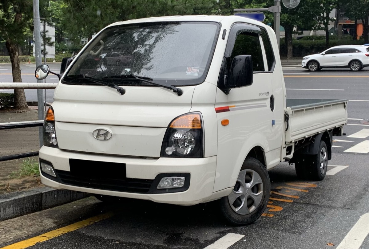 Hyundai H100 açık kasa kamyonet caddede park hâlinde, boş kasasıyla yandan önden görünüm.